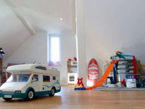 Ein Spielzeugauto steht auf dem Boden, im Hintergrund steht eine Kinder Parkgarage.